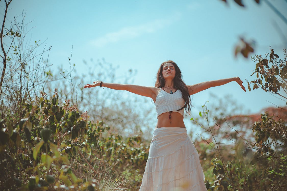woman with arms out in field as she celebrates her emotional well-being during divorce